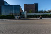 a white building with lots of windows near a street and a bench and fenced off area