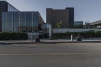 a white building with lots of windows near a street and a bench and fenced off area