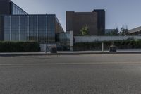 a white building with lots of windows near a street and a bench and fenced off area