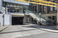 a large concrete building with stairs leading into it on the right side of the street