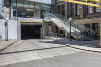 a large concrete building with stairs leading into it on the right side of the street