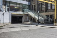 a large concrete building with stairs leading into it on the right side of the street