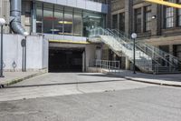 a large concrete building with stairs leading into it on the right side of the street