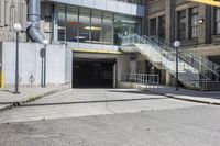 a large concrete building with stairs leading into it on the right side of the street