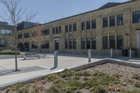 there is an empty courtyard on this large building with lots of green trees on the side