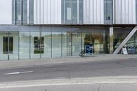 a building with a glass facade on a city street corner with cars parked outside it