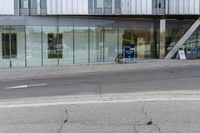 a building with a glass facade on a city street corner with cars parked outside it