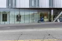 a building with a glass facade on a city street corner with cars parked outside it