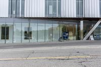 a building with a glass facade on a city street corner with cars parked outside it