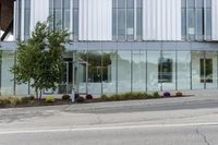 a building with a glass facade on a city street corner with cars parked outside it