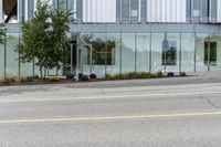 a building with a glass facade on a city street corner with cars parked outside it