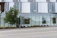 a building with a glass facade on a city street corner with cars parked outside it