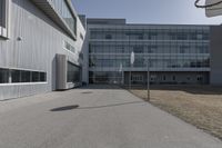 a view of a building outside on a clear day, taken from a road with two cars