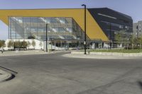 a large modern building with a yellow front and a gray side line at one corner