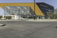 a large modern building with a yellow front and a gray side line at one corner