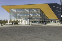 a large modern building with a yellow front and a gray side line at one corner