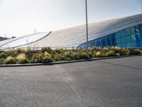 the bus is driving outside the large building in the city near some plants and grass