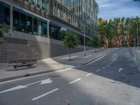 empty street with long, straight walkway next to glassy building and tree lined sidewalk