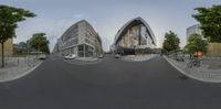 two identical buildings are on the same street together, with bicycles parked near them, and a man and dog in a city