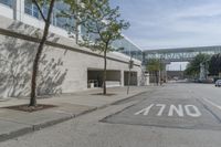 an empty street is next to a walkway in an industrial area that is on the corner and no one is on