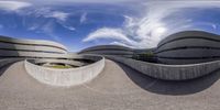 a fish eye view looking at two curved buildings in an office park with a sky background