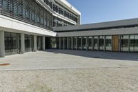 the building has windows and glass doors on both sides of the walkways with a red fire hydrant on each side of it