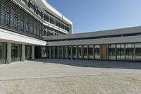 the building has windows and glass doors on both sides of the walkways with a red fire hydrant on each side of it