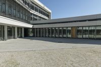 the building has windows and glass doors on both sides of the walkways with a red fire hydrant on each side of it