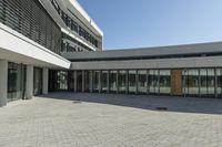 the building has windows and glass doors on both sides of the walkways with a red fire hydrant on each side of it