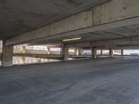 a parking garage filled with empty concrete flooring with parking and stairs in the background