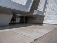 a white building with several steps and large glass panels in the facade is a mosaic that depicts a man