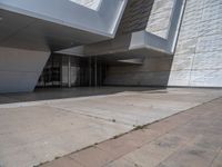 a white building with several steps and large glass panels in the facade is a mosaic that depicts a man