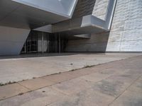 a white building with several steps and large glass panels in the facade is a mosaic that depicts a man