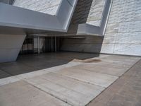 a white building with several steps and large glass panels in the facade is a mosaic that depicts a man