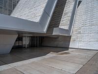 a white building with several steps and large glass panels in the facade is a mosaic that depicts a man