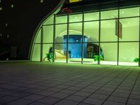 a building with some large windows at night time and plants in the window boxes in front