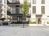 a courtyard with several buildings and a tree in the center of it in front of two balconies