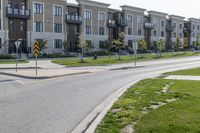 a yellow traffic sign sitting next to a green lawn and sidewalk next to a large apartment building