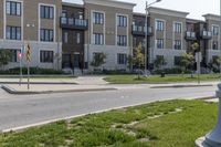 a yellow traffic sign sitting next to a green lawn and sidewalk next to a large apartment building