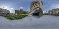 a panorama lens of a curved building at a skate park with some trees in front