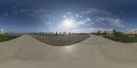 a panoramic view of a skate park near buildings and trees in the distance