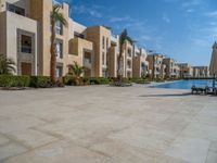 two umbrellas are set by the swimming pool outside of the building to shade the pools