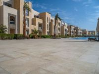 two umbrellas are set by the swimming pool outside of the building to shade the pools