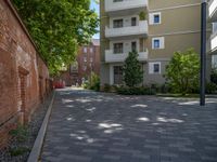 a paved brick street with red trash bins sitting in the middle and trees near to it