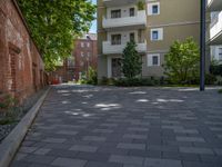 a paved brick street with red trash bins sitting in the middle and trees near to it