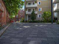 a paved brick street with red trash bins sitting in the middle and trees near to it