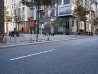 an empty city street with buildings and a bike parked on the sidelines of the street