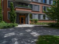 a residential driveway with a bench and bushes in between buildings and green grass on either side