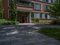 a residential driveway with a bench and bushes in between buildings and green grass on either side