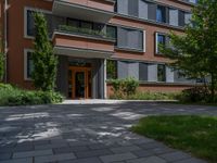 a residential driveway with a bench and bushes in between buildings and green grass on either side